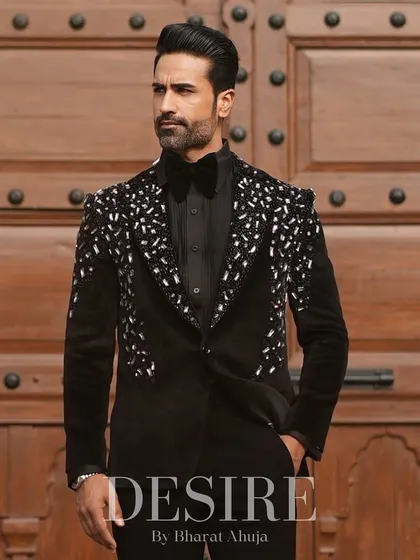 A full-length shot of the black velvet tuxedo against a grand wooden door. The look is one of pure, undeniable sophistication and power.