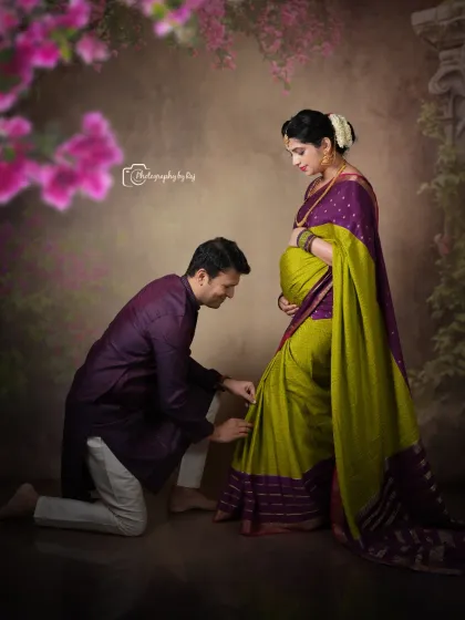 A tender studio moment where the father-to-be helps his wife with her saree, a beautiful detail to capture.