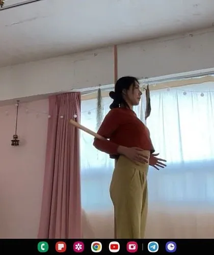 Using a simple prop like a stick at home can provide excellent feedback for postural alignment. Here, I am guiding a student online to feel the correct position of her thoracic spine.