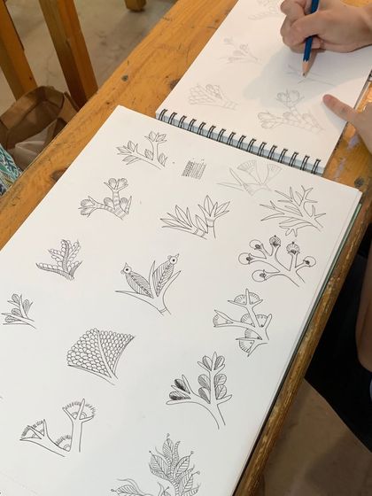 Practicing Gond motifs in a sketchbook. We believe in building a strong foundation by mastering the basic elements of each art form.