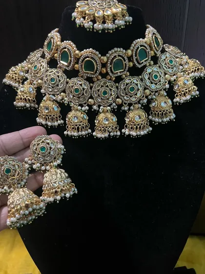 A close-up view of the intricate work on our green choker set. The combination of green stones, white pearls, and gold-tone filigree makes it look incredibly rich.