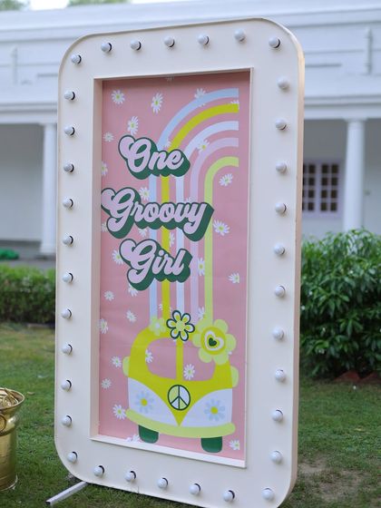 The "One Groovy Girl" sign stands proudly at the entrance of the outdoor venue, welcoming guests to a fun and retro-themed celebration.