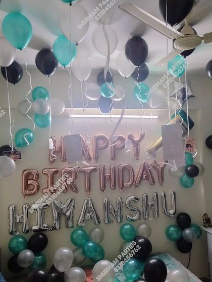 A birthday room decoration with a mix of teal, black, and silver balloons.