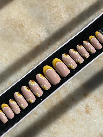 Sunflowers and sunshine to brighten your day. This custom set features hand-painted daisies and a cheerful yellow French tip design on a nude base. It's a happy, floral design perfect for any season.