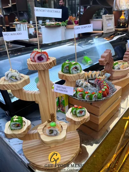 An artistic display of our sushi on a wooden tree stand, with each roll labelled, including Spicy Avocado, Shiitake Mushroom, and Corn Tempura.