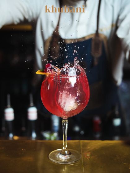 One sip, and the weekend officially begins. A bartender creates a dramatic splash in this vibrant red cocktail, capturing the energy of our bar.