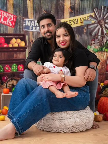 Welcome to the farm. This creative and fun setup features a rustic backdrop with signs, crates of vegetables, and pumpkins, perfect for a unique family photoshoot.