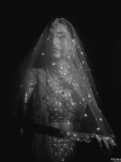 An artistic black and white portrait of the bride, her face partially obscured by a glittering veil, creating a sense of mystery and elegance.