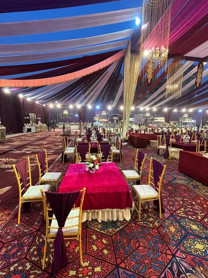 A wide view of the guest dining area, with a colorful patterned carpet and a ceiling draped in rich purple, white, and gold fabrics.