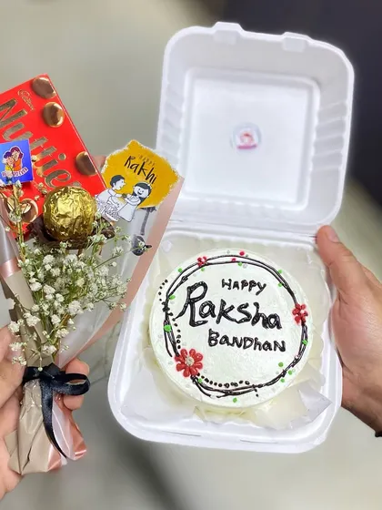 Another angle of our popular Rakhi hamper, showing the hand-piped details on the bento cake and the cute Rakhi-themed tags on the chocolate bouquet.
