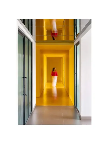The reflective ceiling in this corridor of 'The Amber Encase' creates a surreal, inverted reflection, adding a layer of artistic abstraction to the functional space.