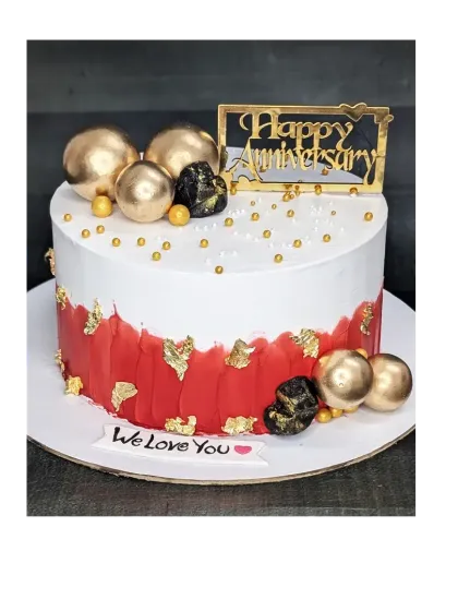 A modern anniversary cake with a bold red and white design, accented with gold leaf and chocolate spheres. This is a rich chocolate truffle cake, perfect for a stylish celebration.