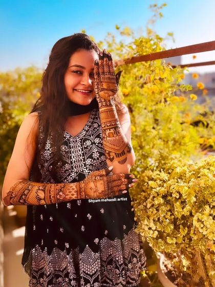 The client smiling and posing, giving a great view of her full-arm mehandi design.