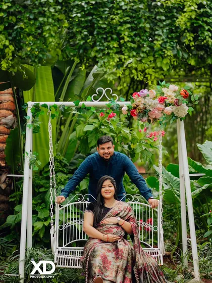A happy couple enjoying a moment on a garden swing, surrounded by lush greenery and flowers.