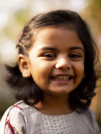 A big, happy grin that lights up her whole face. This close-up portrait is a beautiful, joyful memory from her third birthday celebration.