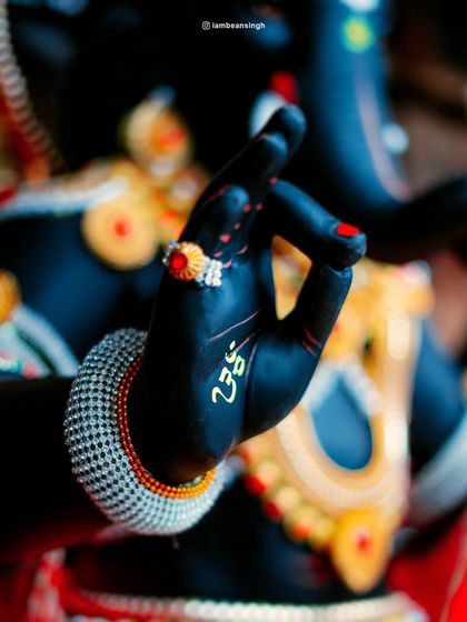 A close-up of the Ganpati idol's hand in a gesture of blessing. The intricate details, from the ring to the bracelet, highlight the artistry and devotion poured into its creation.