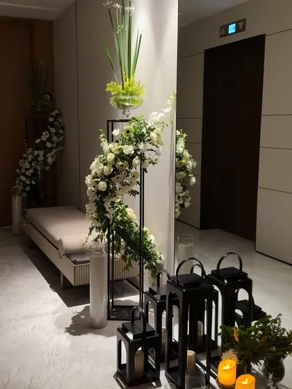 The entryway decor illuminated by candlelight. The black lanterns and white candles provide a beautiful contrast to the white flowers and light colored walls.