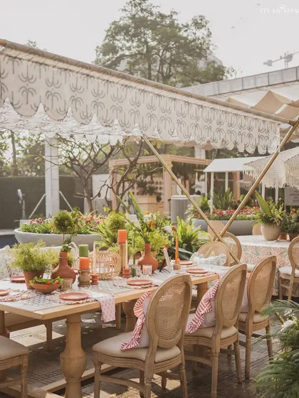 A long dining table setup with cane-back chairs and a custom-printed canopy, perfect for a large group brunch.