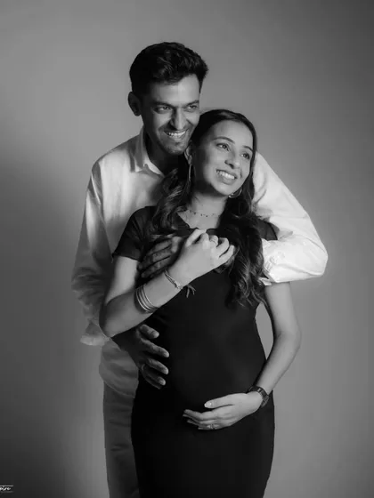 A joyful, candid moment captured in timeless black and white. The couple's laughter and embrace show the happiness and excitement of their pregnancy journey.