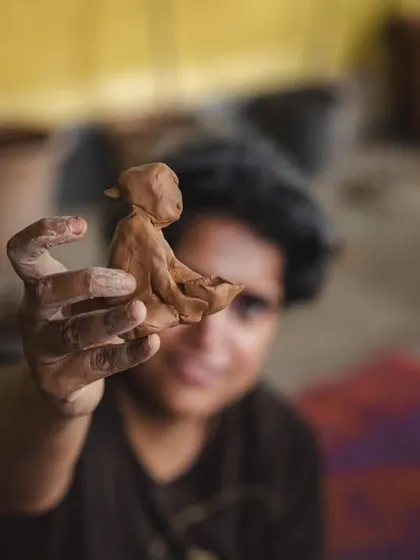 Sometimes, the most profound stories are held in the smallest of things. A participant holds up a figure she created during a clay workshop. This is a moment of pure creation, a tangible piece of a personal journey made visible through art.
