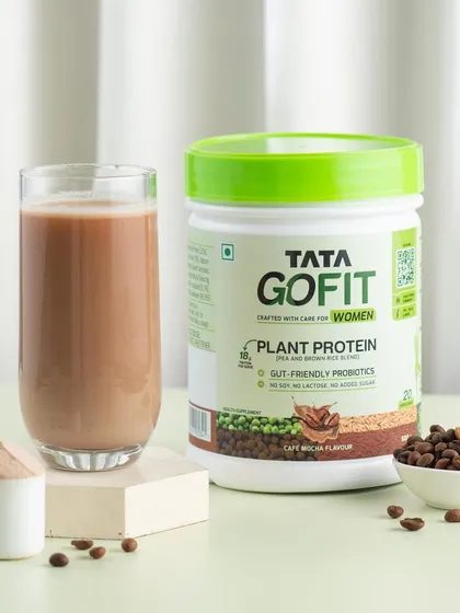 A simple and clean shot of the prepared protein shake next to the product tub, with a few coffee beans to hint at the mocha flavor.