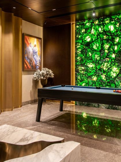 Another view of the backlit green stone wall next to the pool table. The reflection on the polished floor enhances the dramatic effect of this unique design element.