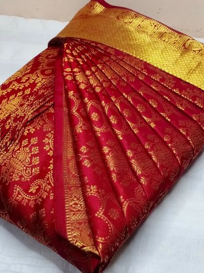 This classic red and gold bridal saree is a favorite for weddings. My pre-pleating service ensures the heavy fabric is manageable and drapes perfectly every time.