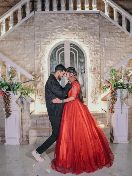 A romantic dance pose in front of a beautifully lit stone facade. The bride's flowing red gown and the elegant setting are perfect for a fairytale-themed shoot.