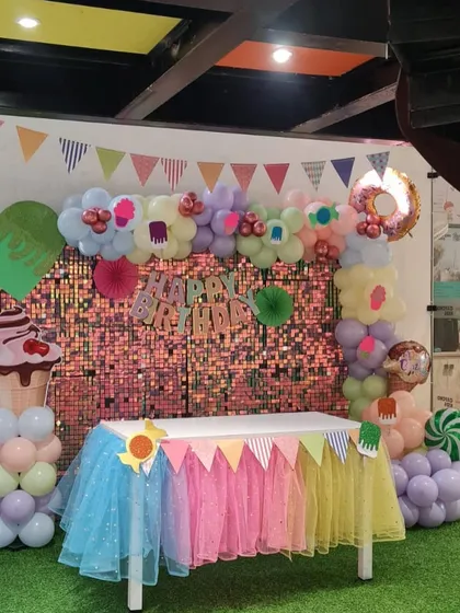 A sweet Candyland-themed party setup with a colorful dessert table and decorations shaped like ice cream and donuts.