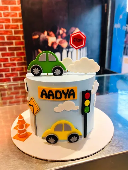 A simple and fun car-themed cake with fondant cars, traffic lights, and road signs.