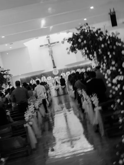 A wide, atmospheric shot of a church wedding ceremony. The blur and angle give a sense of being present in the moment, capturing the solemnity and beauty of the space.