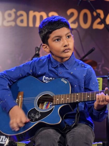 A close-up of a young guitarist during the instrumental tribute to Puneeth Rajkumar.