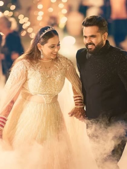 A client making a memorable entrance at his reception. He is wearing a custom black bandhgala with subtle, intricate texture, proving that elegance is all in the details.
