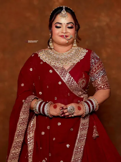 A classic pose showing the intricate details of the bridal attire and makeup. The rich red tones are perfectly balanced with gold and kundan jewelry.