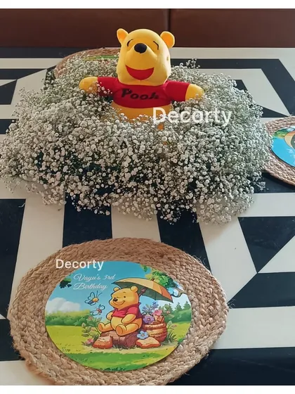 A sweet Winnie the Pooh centerpiece featuring a Pooh plushie in a nest of baby's breath flowers.
