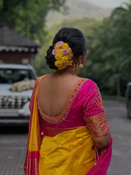 A back view showcasing the detailed embroidery on the blouse and the neat, full floral bun.