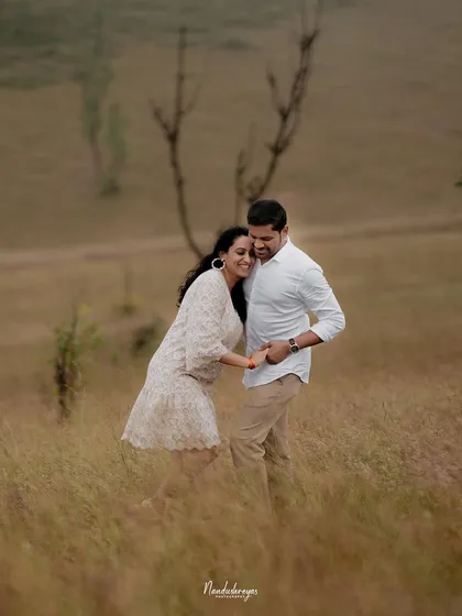 A couple shares a candid moment in a grassy field, their laughter and interaction showing the fun side of an adventure shoot.