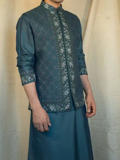 Step into the world of elegance with this stunning silk teal kurta pajama and jacket set, adorned with intricate Resham silk embroideries.