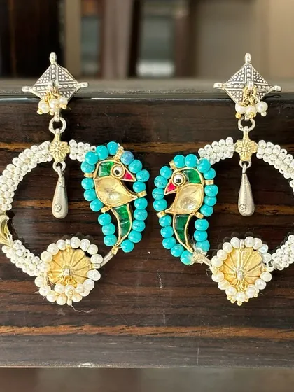 These fusion hoop earrings are truly iconic. They feature a colourful enamel parrot motif on a beaded hoop, combining oxidised silver with gold-plated details for a unique, artistic look.