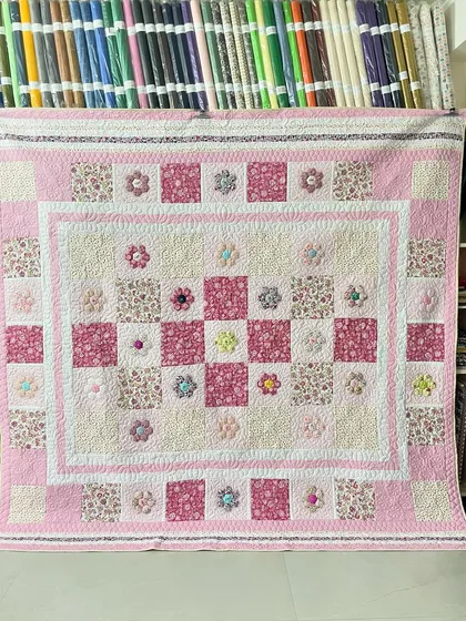 A lovely hexagon quilt in shades of pink and cream, with delicate 3D flower details.