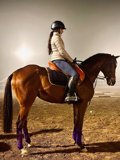 A rider and her horse stand poised in the arena during a foggy evening session. Our floodlit arenas allow for training even after the sun goes down.