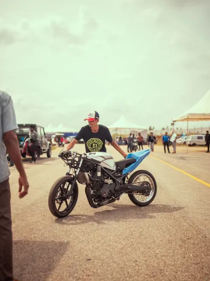 A participant pushes his stripped-down custom drag bike, a lightweight machine built for maximum acceleration.