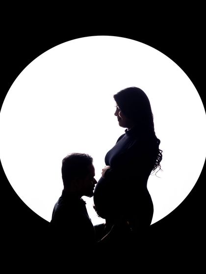 A classic and tender silhouette. The father-to-be gently kisses the baby bump, a gesture full of love and anticipation for the little one's arrival.