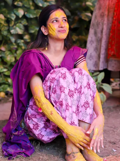 The bride enjoying a quiet moment during her Haldi. This full-length shot captures her in her traditional attire, surrounded by the festive atmosphere.