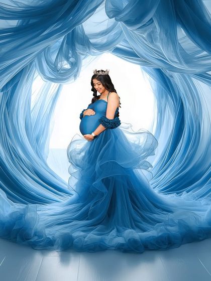 A stunning, high-concept portrait where the mother-to-be is surrounded by waves of flowing blue fabric. Her serene expression and the crown on her head add to the majestic, queen-of-the-sea feel.