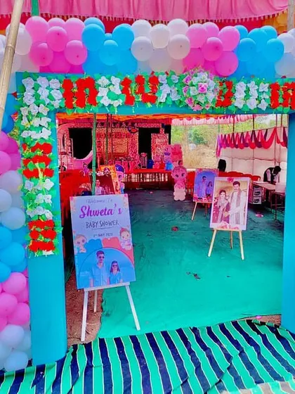 A grand entrance for a baby shower in a pandal, with a floral and balloon arch and personalized welcome signs.