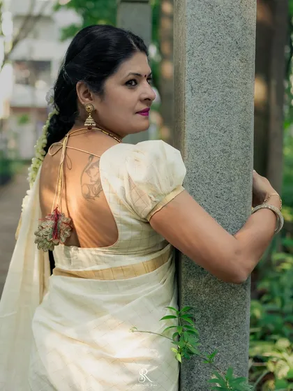 A modern take on the classic Kerala saree. This look features a custom blouse with puffed sleeves and a tie-up back, adding a personal touch to the timeless elegance of Onam attire.