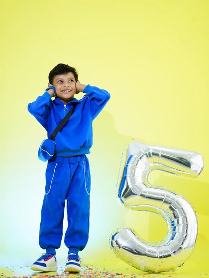 A playful shot from a fifth birthday celebration, with the birthday boy looking happy amidst confetti and a large balloon.