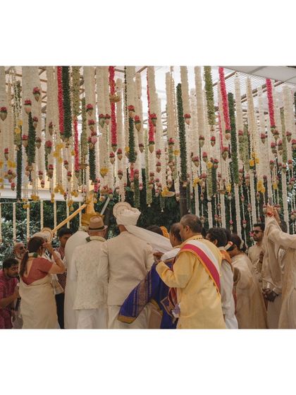 A moment of ritual during the ceremony, with the dense floral ceiling creating an intimate and sacred atmosphere.