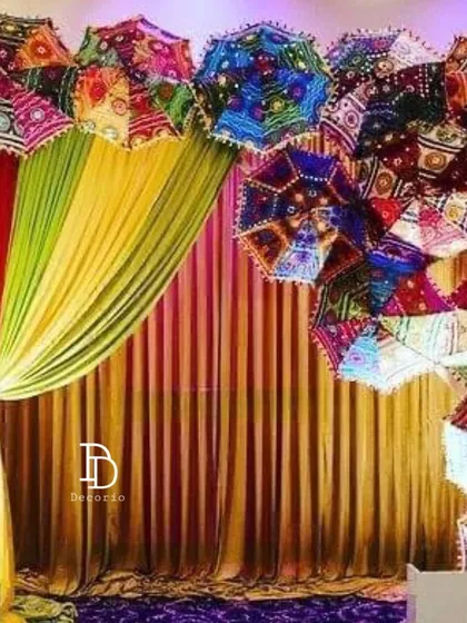 For a vibrant mehndi night, I used a canopy of colorful Rajasthani umbrellas. This creates a festive ceiling effect over the main area, paired with rich, colorful drapes for a truly celebratory feel.